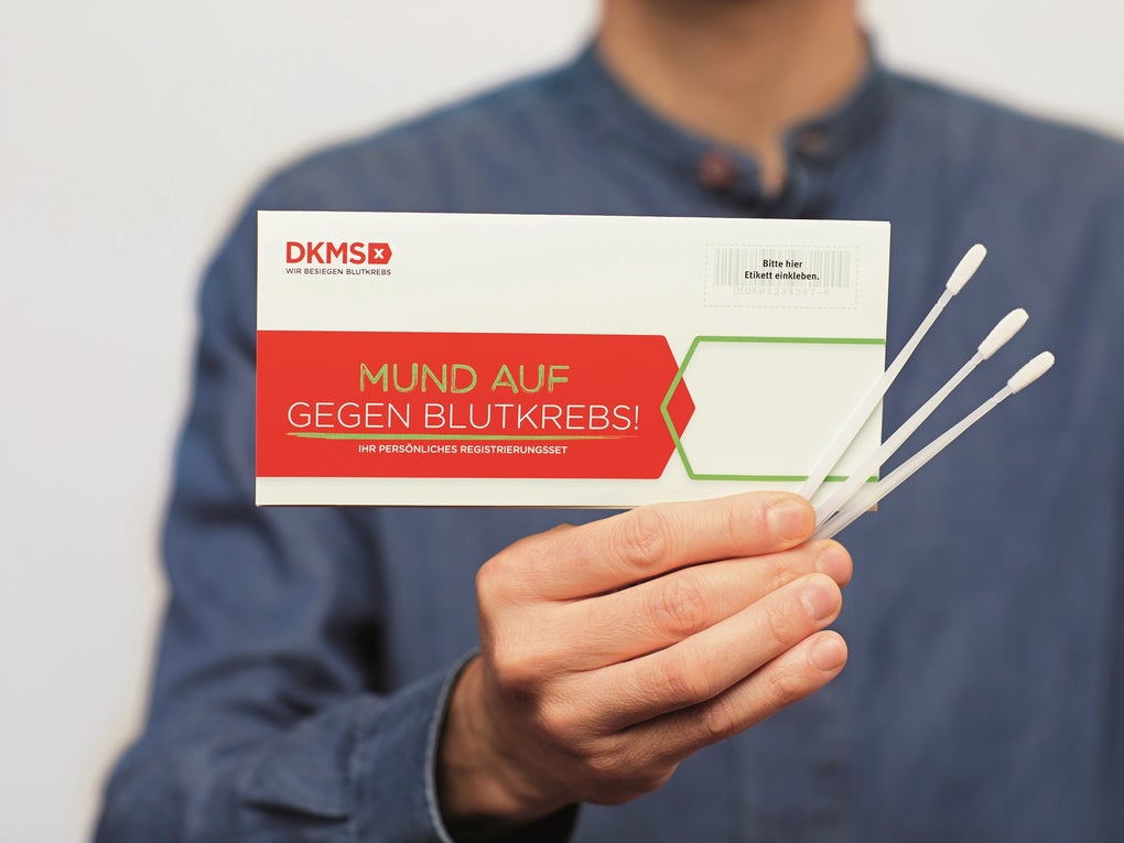 Eine Person in blauer Kleidung hält das DKMS-Registrierungsset mit der Aufschrift „Mund auf gegen Blutkrebs!“ sowie drei Wangenabstrichstäbchen in der Hand Eine Person in blauer Kleidung hält das DKMS-Registrierungsset mit der Aufschrift „Mund auf gegen Blutkrebs!“ sowie drei Wangenabstrichstäbchen in der Hand