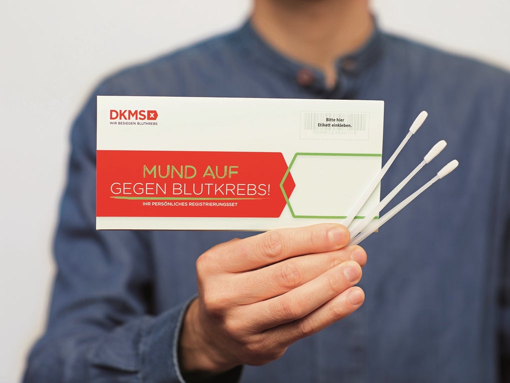 Eine Person in blauer Kleidung hält das DKMS-Registrierungsset mit der Aufschrift „Mund auf gegen Blutkrebs!“ sowie drei Wangenabstrichstäbchen in der Hand Eine Person in blauer Kleidung hält das DKMS-Registrierungsset mit der Aufschrift „Mund auf gegen Blutkrebs!“ sowie drei Wangenabstrichstäbchen in der Hand