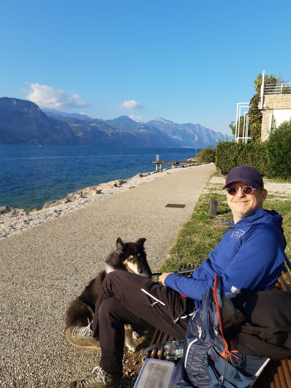 Patient Holger sitzt am Wasser auf einer Bank und lächelt. Patient Holger sitzt am Wasser auf einer Bank und lächelt.