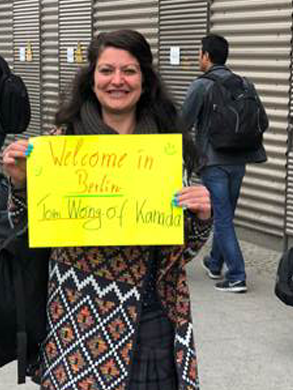 Eine Frau hält ein gelbes Schild mit "Welcome in Berlin"