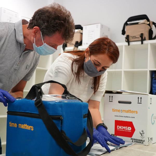 Foto von zwei Mitarbeiterinnnen - einer nimmt Stammzellen in einer Transportbox entgegen, die andere dokumentiert den Prozess Foto von zwei Mitarbeiterinnnen - einer nimmt Stammzellen in einer Transportbox entgegen, die andere dokumentiert den Prozess