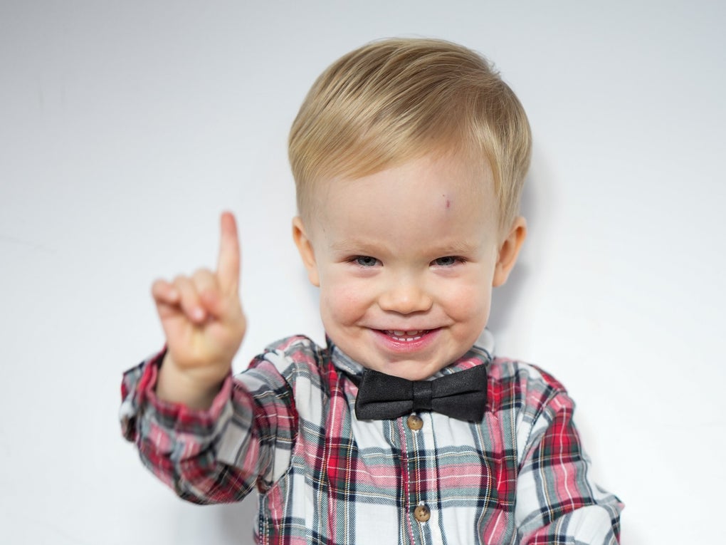 ein kleiner Junge lacht in die Kamera und hält seinen Zeigefinger hoch ein kleiner Junge lacht in die Kamera und hält seinen Zeigefinger hoch