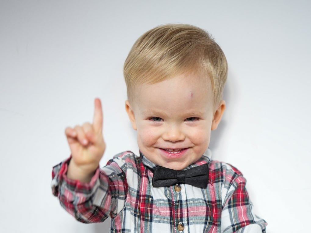 ein kleiner Junge lacht in die Kamera und hält seinen Zeigefinger hoch ein kleiner Junge lacht in die Kamera und hält seinen Zeigefinger hoch