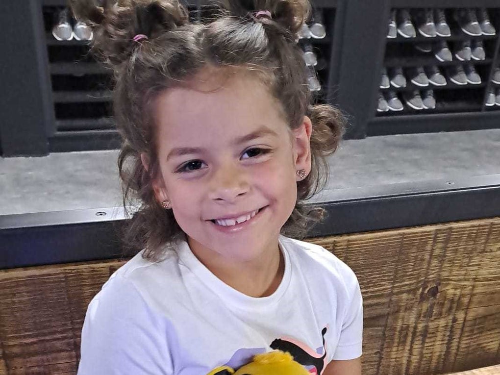 Ein kleines Mädchen mit lockigem Haar und mehreren Zöpfen sitzt auf einer Bank. Sie trägt ein weißes T-Shirt und hält ein Plüschtier aus dem Film „Der König der Löwen“ im Arm. Im Hintergrund ist ein Regal mit zahlreichen Paar Schuhen zu sehen. Ein kleines Mädchen mit lockigem Haar und mehreren Zöpfen sitzt auf einer Bank. Sie trägt ein weißes T-Shirt und hält ein Plüschtier aus dem Film „Der König der Löwen“ im Arm. Im Hintergrund ist ein Regal mit zahlreichen Paar Schuhen zu sehen.