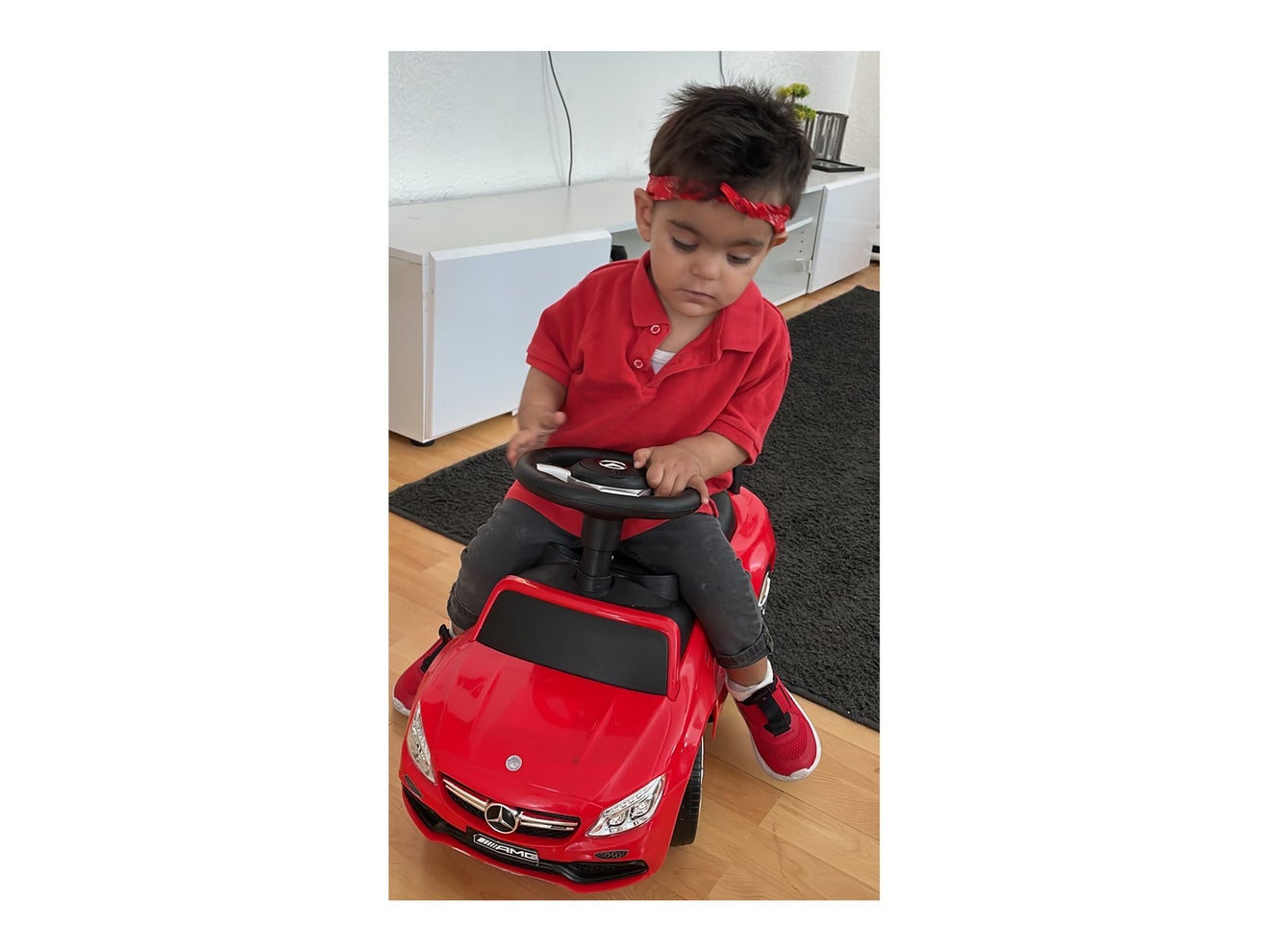 Patient Poyraz sitzt auf einem roten Kinderauto.
