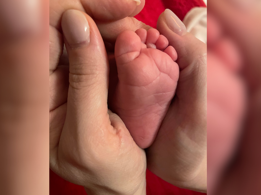 Der Fuß eines Babys in der Hand eines Menschen Der Fuß eines Babys in der Hand eines Menschen