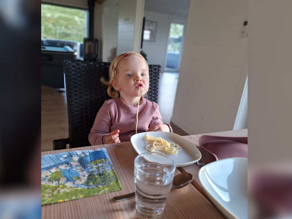 Ein kleines Mädchen sitzt an einem Tisch und isst Spaghetti. Ein kleines Mädchen sitzt an einem Tisch und isst Spaghetti.