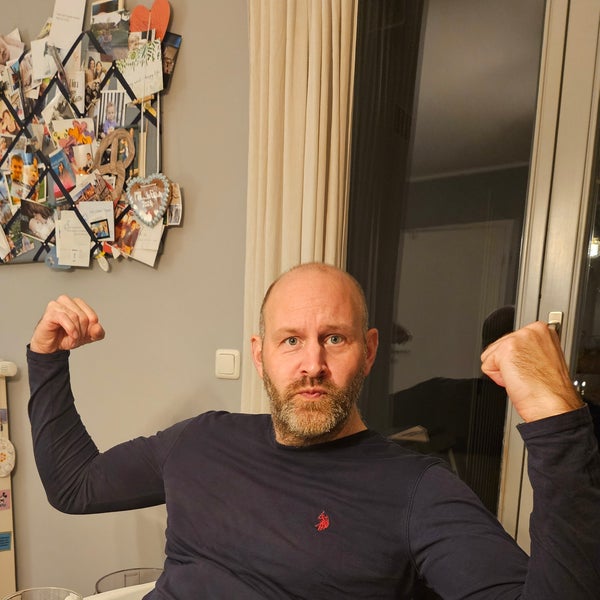 Ein Mann sitzt mit erhobenen Armen auf einem Stuhl Ein Mann sitzt mit erhobenen Armen auf einem Stuhl