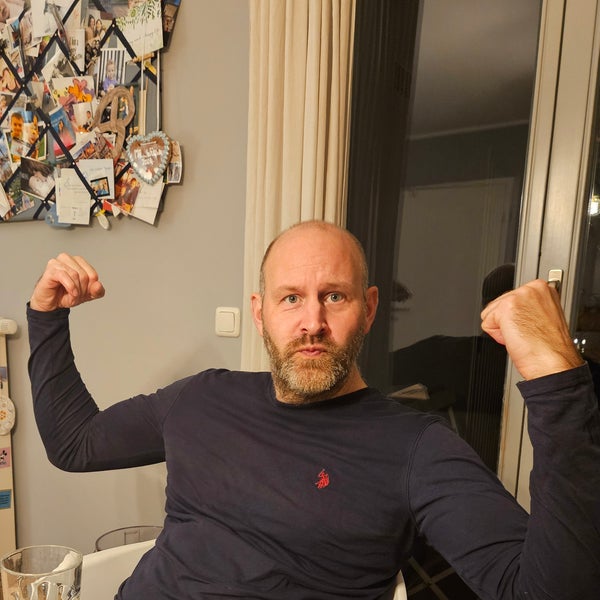 Ein Mann sitzt mit erhobenen Armen auf einem Stuhl Ein Mann sitzt mit erhobenen Armen auf einem Stuhl