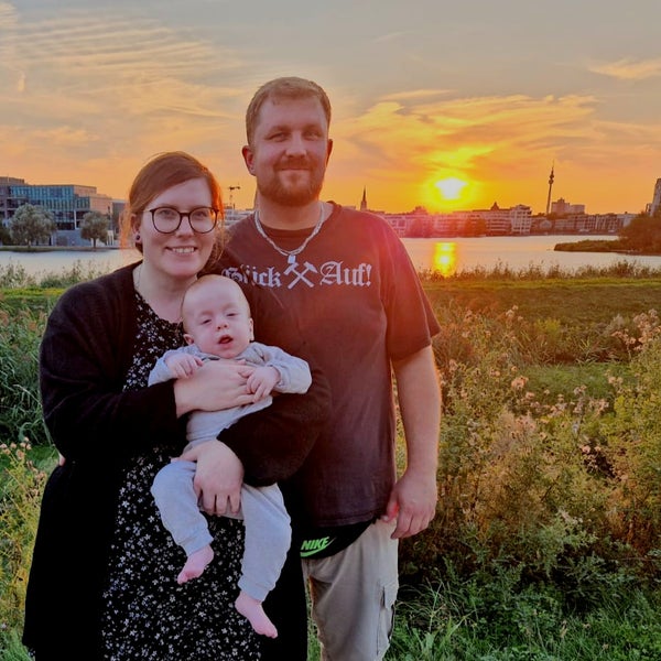 Ein Mann und eine Frau halten ein Baby vor einem Sonnenuntergang Ein Mann und eine Frau halten ein Baby vor einem Sonnenuntergang