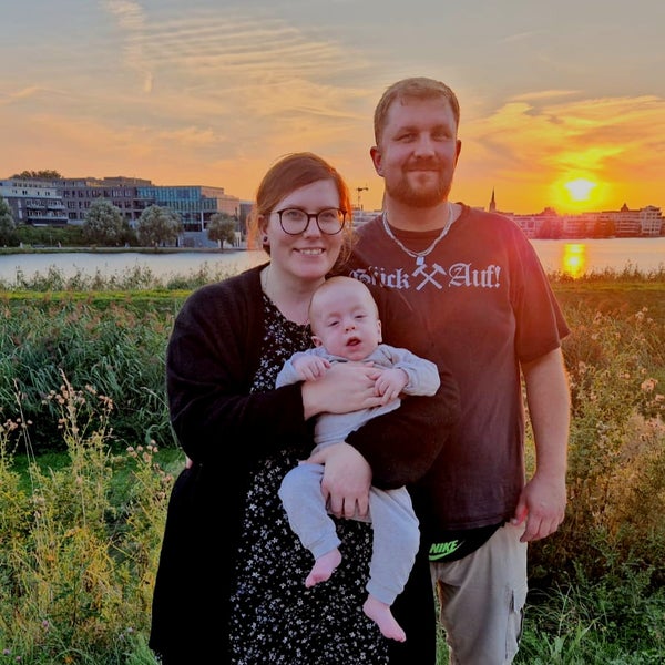 Ein Mann und eine Frau halten ein Baby vor einem Sonnenuntergang Ein Mann und eine Frau halten ein Baby vor einem Sonnenuntergang