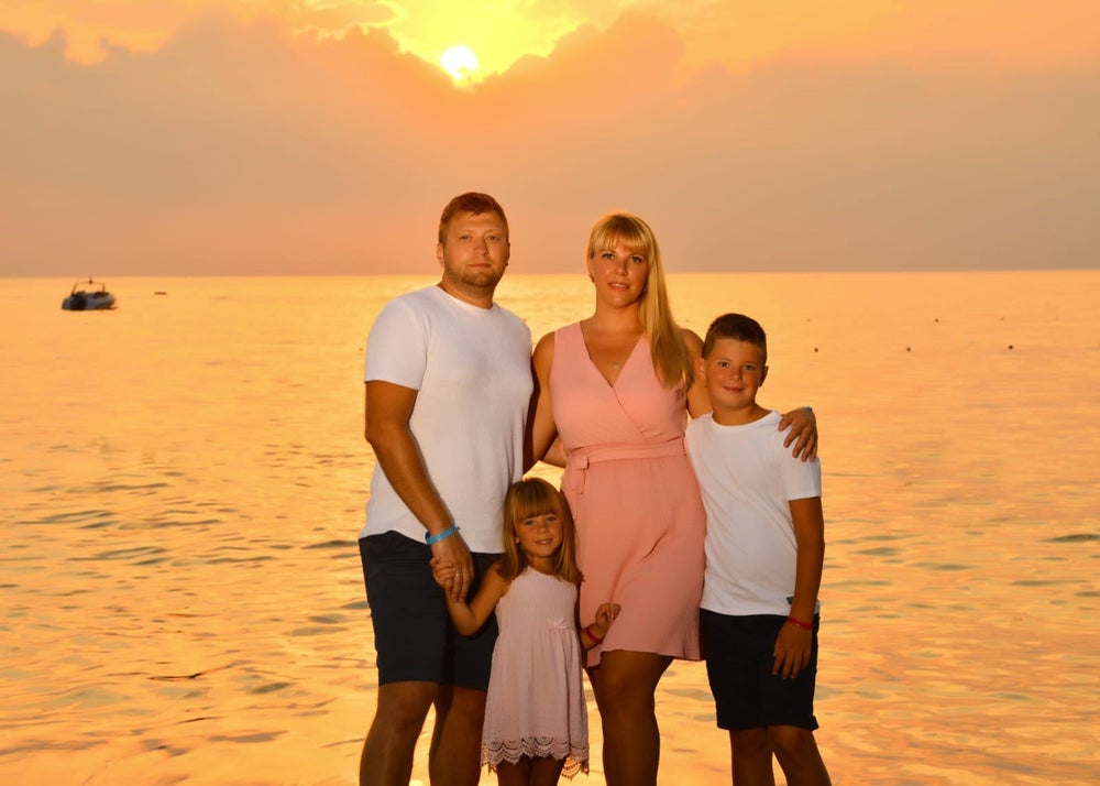 Patientin Julia, ihr Mann und ihre zwei Kinder bei Sonnenuntergang am Strand