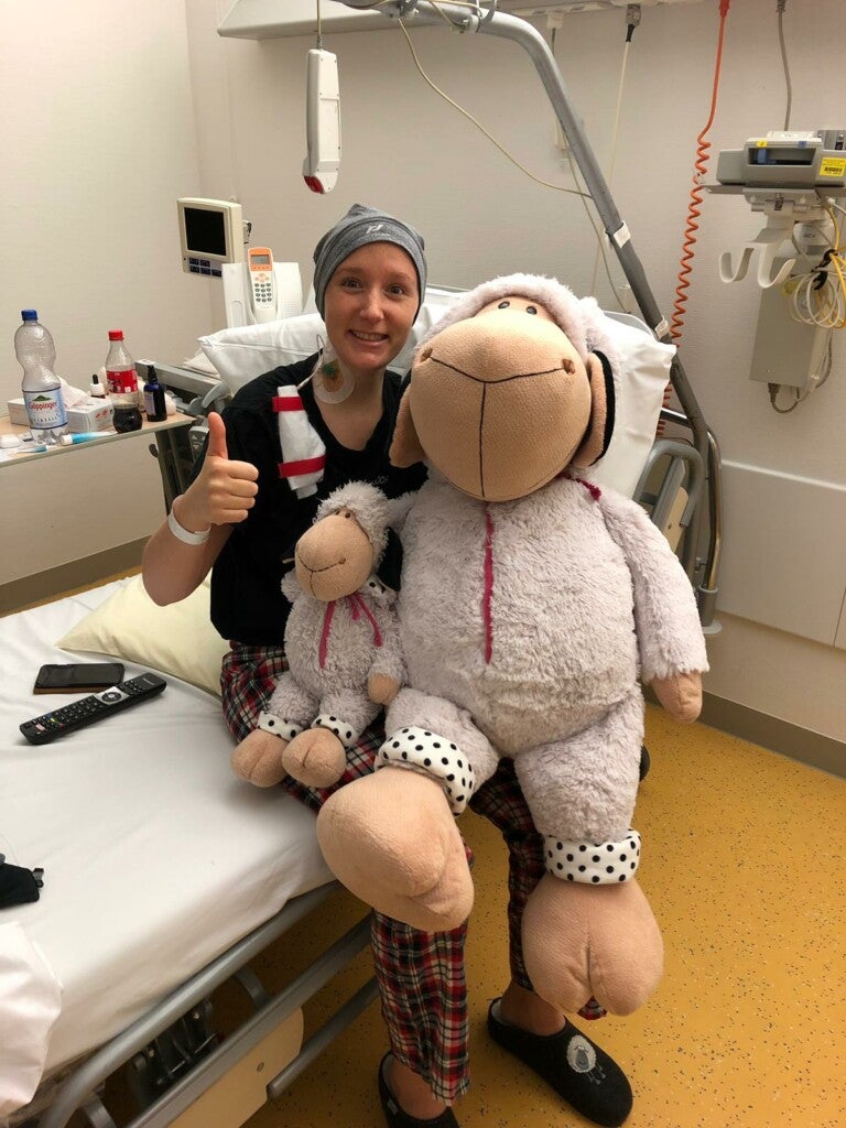 Eine Frau sitzt auf einem Krankenhausbett und hält ein Stofftier Eine Frau sitzt auf einem Krankenhausbett und hält ein Stofftier