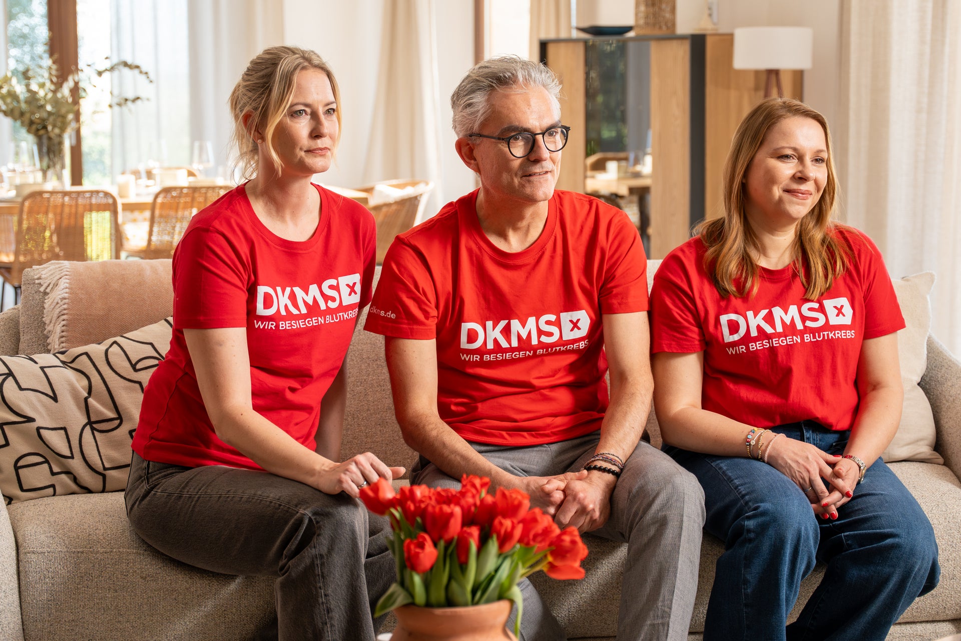 Eine Gruppe von Menschen sitzt auf einer Couch Eine Gruppe von Menschen sitzt auf einer Couch
