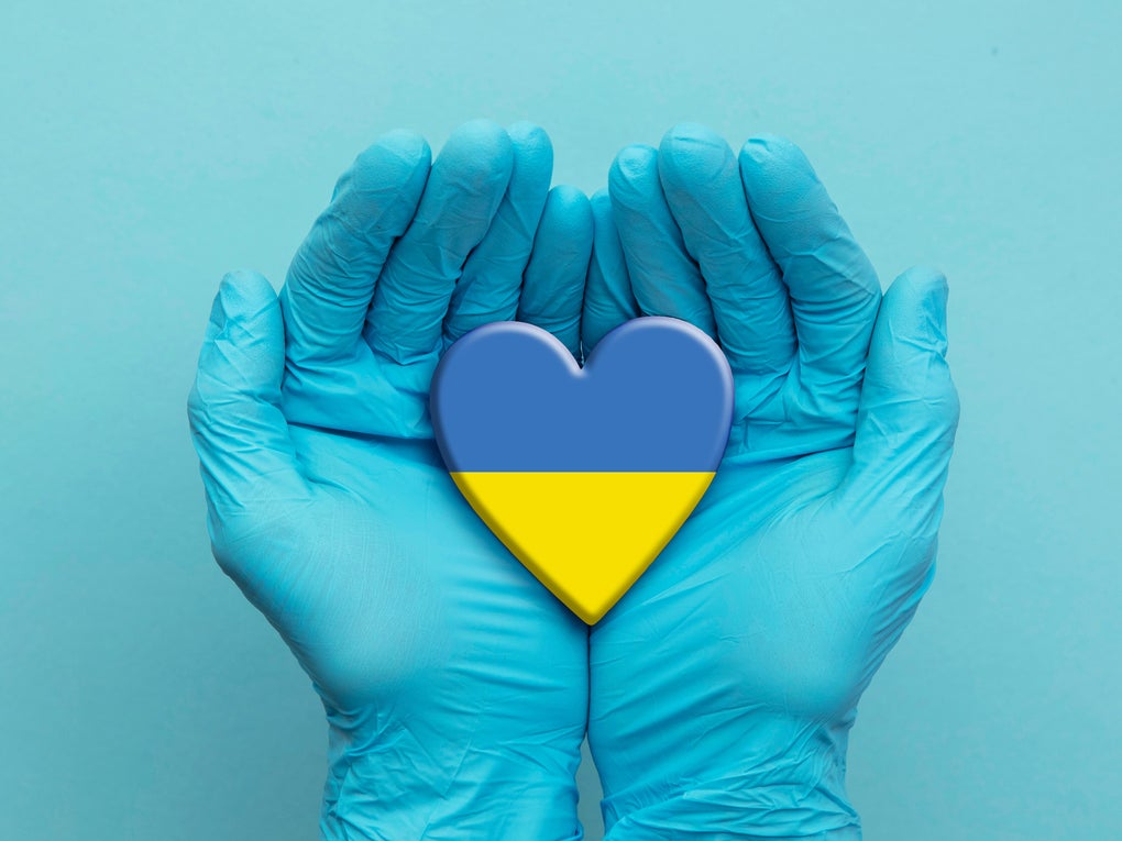 Hände in blauen Handschuhen halten ein Herz in den Farben der Ukraine Flagge Hände in blauen Handschuhen halten ein Herz in den Farben der Ukraine Flagge