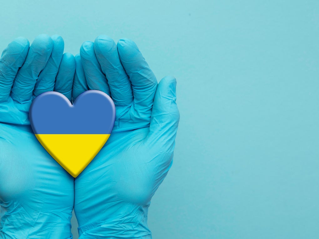 Hände in blauen Handschuhen halten ein Herz in den Farben der Ukraine Flagge Hände in blauen Handschuhen halten ein Herz in den Farben der Ukraine Flagge