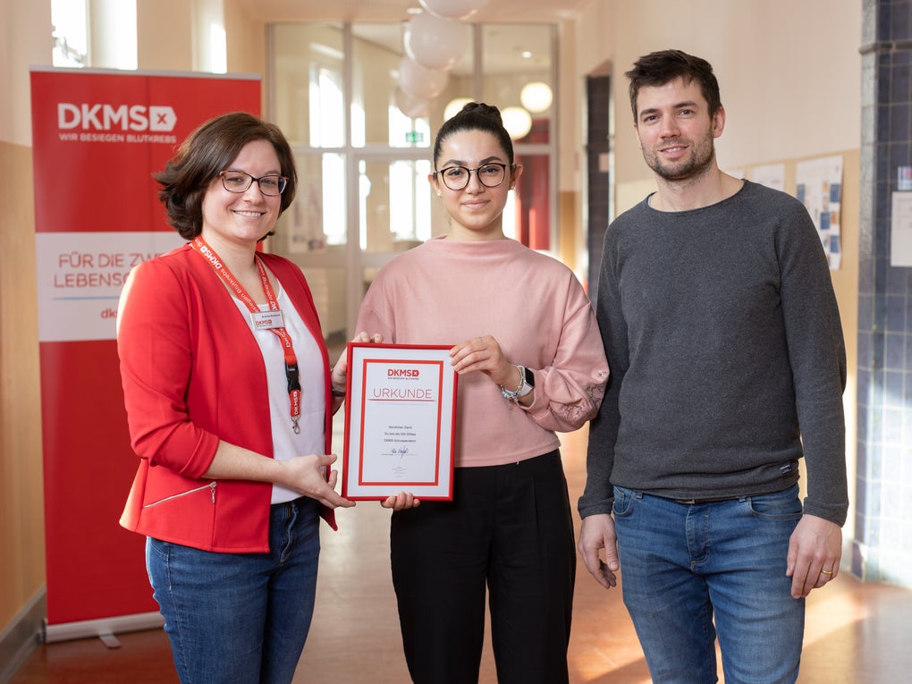 Eine Gruppe von Menschen posiert für ein Foto, sie halten eine Urkunde in der Hand Eine Gruppe von Menschen posiert für ein Foto, sie halten eine Urkunde in der Hand