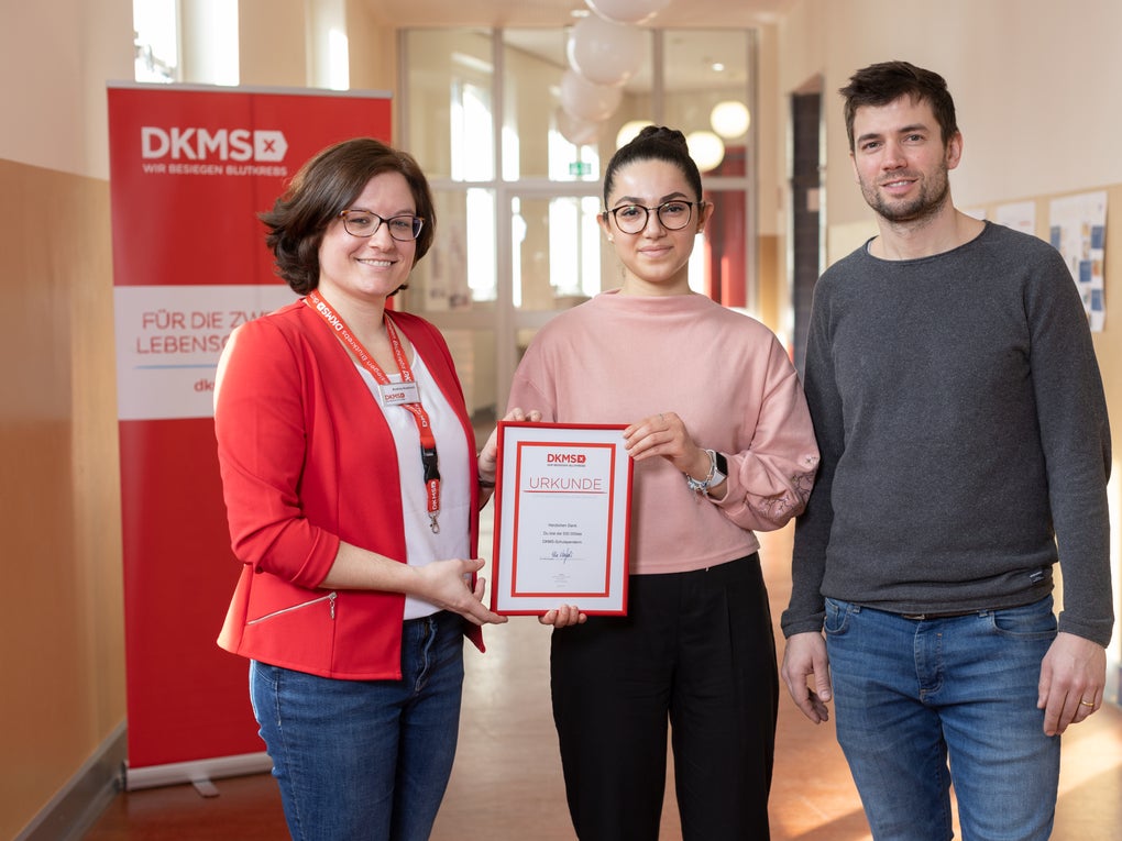 Eine Gruppe von Menschen posiert für ein Foto, sie halten eine Urkunde in der Hand Eine Gruppe von Menschen posiert für ein Foto, sie halten eine Urkunde in der Hand