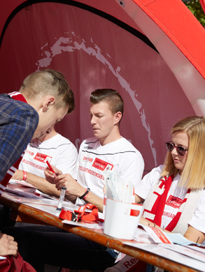 Eine Gruppe von Menschen, die an einem Tisch sitzen bei einer Registrierungsaktion der DKMS