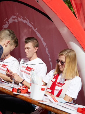 Eine Gruppe von Menschen, die an einem Tisch sitzen bei einer Registrierungsaktion der DKMS