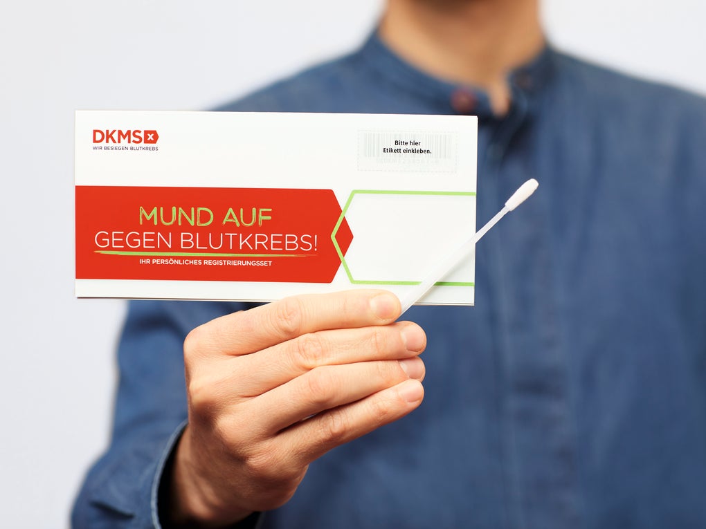 Eine Person mit einer Karte von der DKMS und einem Wattestäbchen in der Hand Eine Person mit einer Karte von der DKMS und einem Wattestäbchen in der Hand