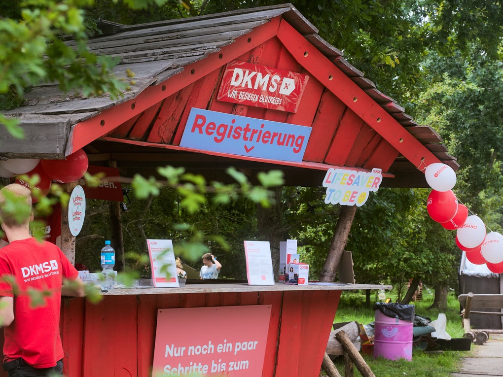 Ein Mann steht an einem kleinen roten Stand Ein Mann steht an einem kleinen roten Stand