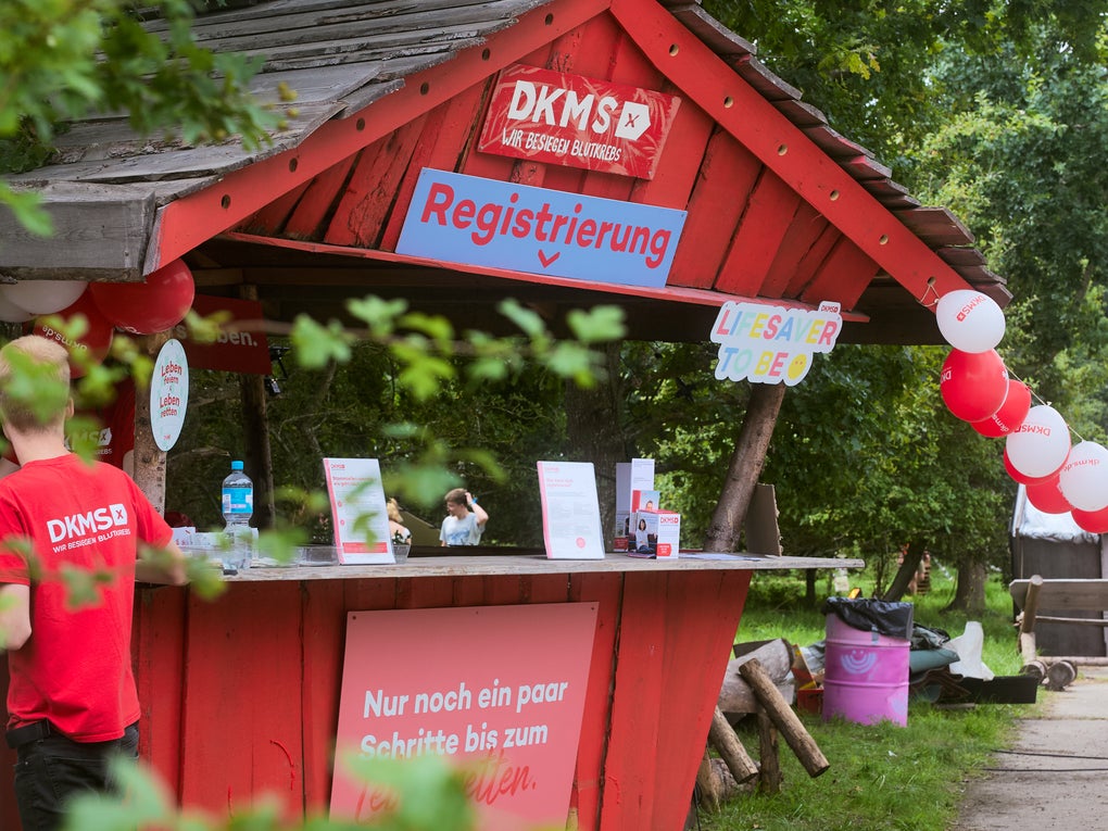 Ein Mann steht an einem kleinen roten Stand Ein Mann steht an einem kleinen roten Stand