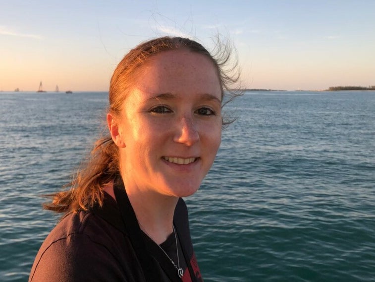 Eine Frau lächelt in die Kamera. Im Hintergrund sieht man Meer. Eine Frau lächelt in die Kamera. Im Hintergrund sieht man Meer.