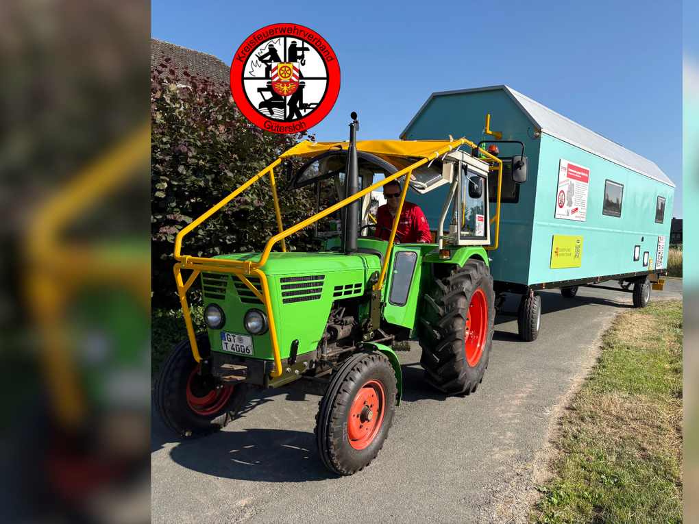 Ein Mann fährt einen grünen Traktor, der einen türkisfarbenen Bauwagen zieht. Ein Mann fährt einen grünen Traktor, der einen türkisfarbenen Bauwagen zieht.