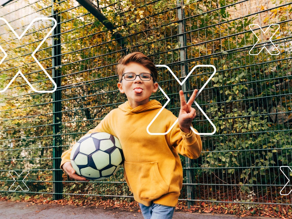 Ein Junge, der einen Fußball hält und seine Zunge herausstreckt Ein Junge, der einen Fußball hält und seine Zunge herausstreckt