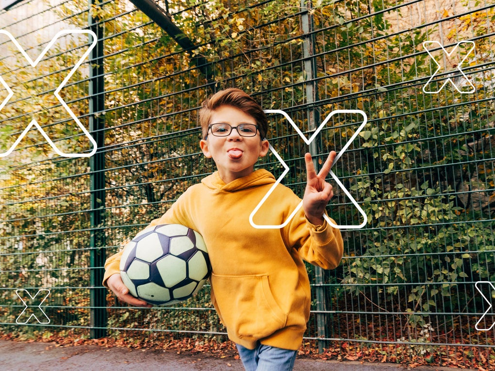 Ein Junge, der einen Fußball hält und seine Zunge herausstreckt Ein Junge, der einen Fußball hält und seine Zunge herausstreckt