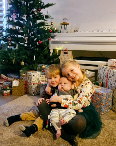 Kleiner Blutkrebspatient Nils mit 2 größeren Geschwistern unter dem Weihnachtsbaum