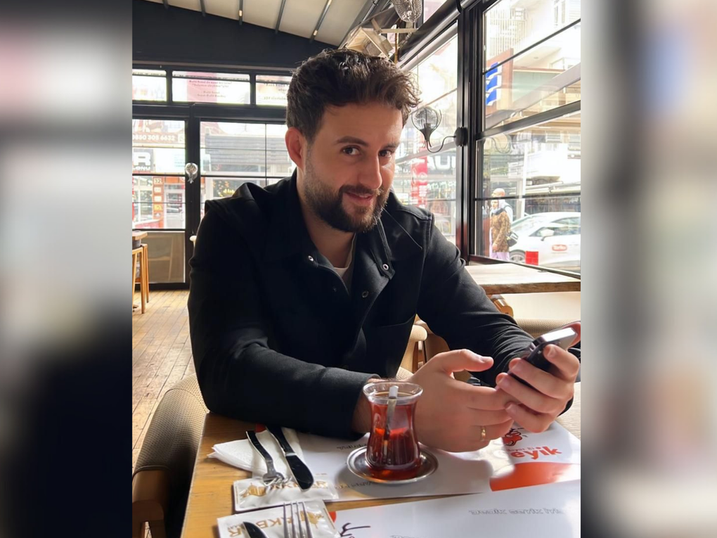 Ein Mann sitzt an einem Tisch und hält ein Smartphone in den Händen. Ein Mann sitzt an einem Tisch und hält ein Smartphone in den Händen.