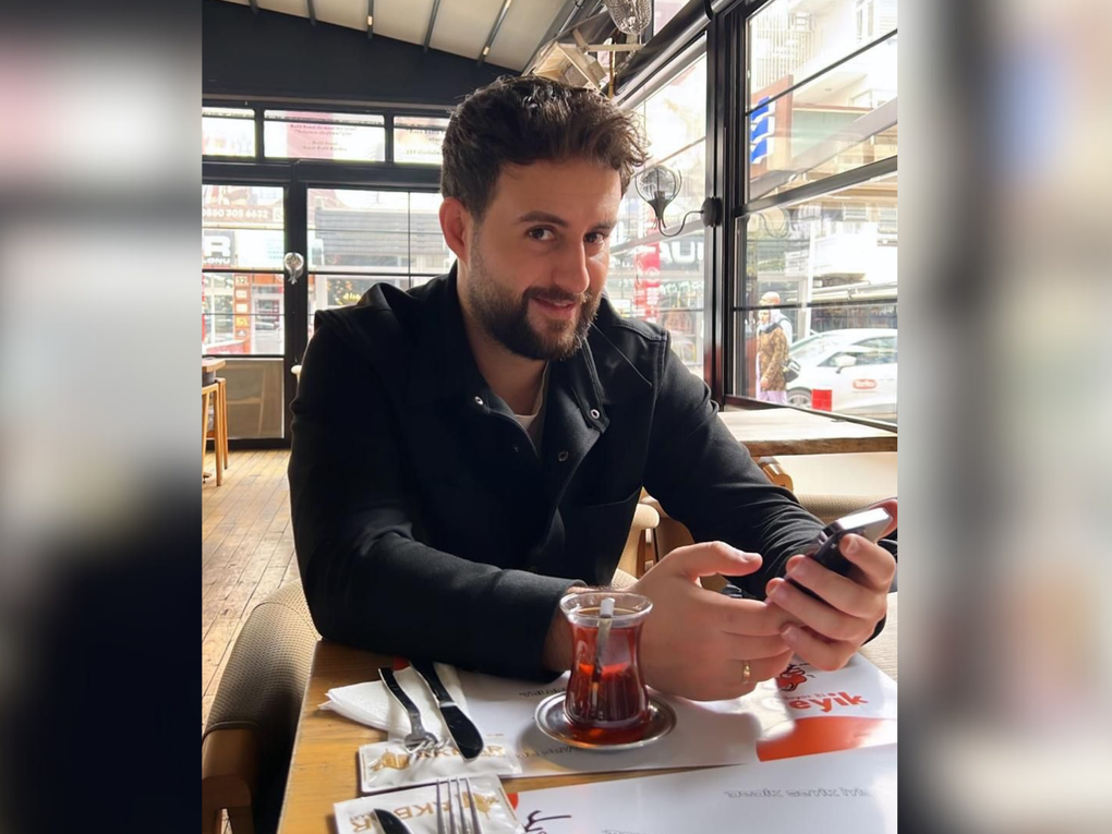 Ein Mann sitzt an einem Tisch und hält ein Smartphone in den Händen. Ein Mann sitzt an einem Tisch und hält ein Smartphone in den Händen.