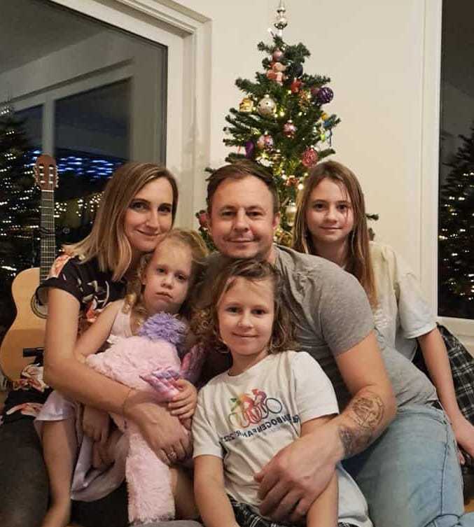 zwei Eltern mit ihren drei Kindern vor einem Weihnachtsbaum zwei Eltern mit ihren drei Kindern vor einem Weihnachtsbaum