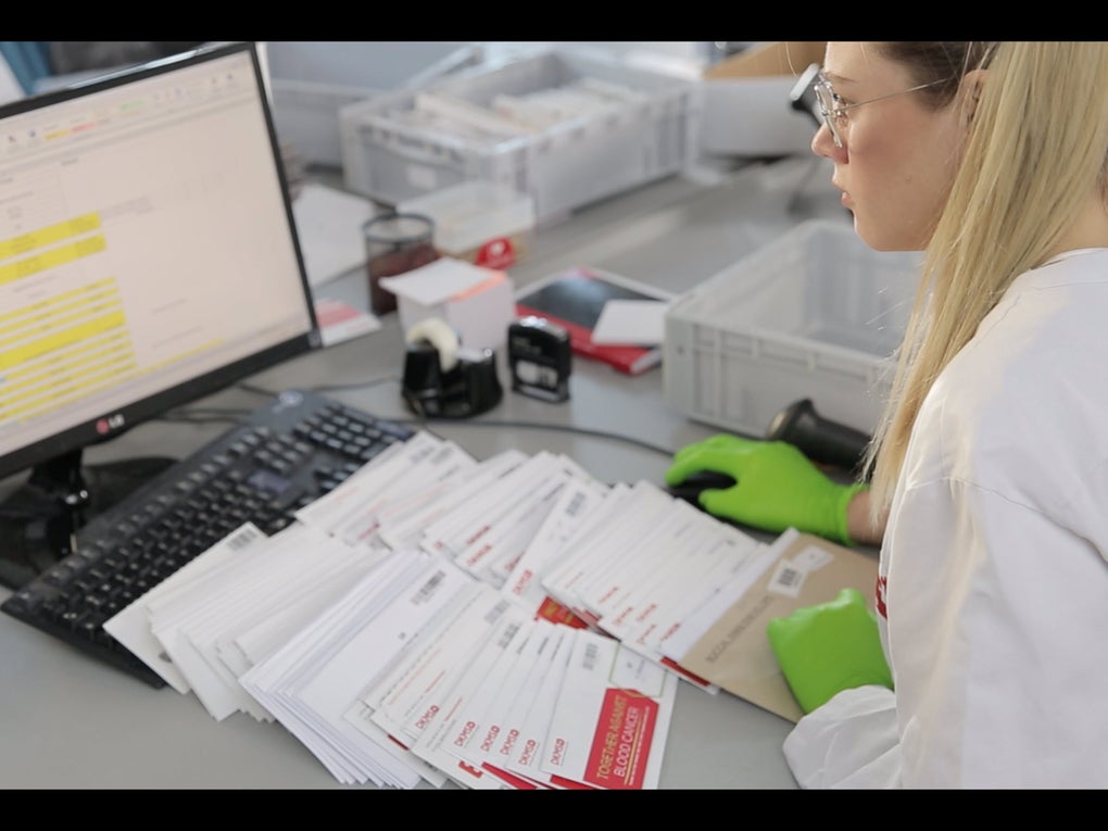 Eine Frau im Laborkittel und mit Handschuhen schaut auf einen Computerbildschirm Eine Frau im Laborkittel und mit Handschuhen schaut auf einen Computerbildschirm