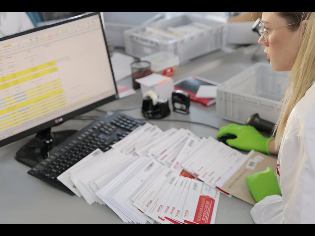 Eine Frau im Laborkittel und mit Handschuhen schaut auf einen Computerbildschirm Eine Frau im Laborkittel und mit Handschuhen schaut auf einen Computerbildschirm