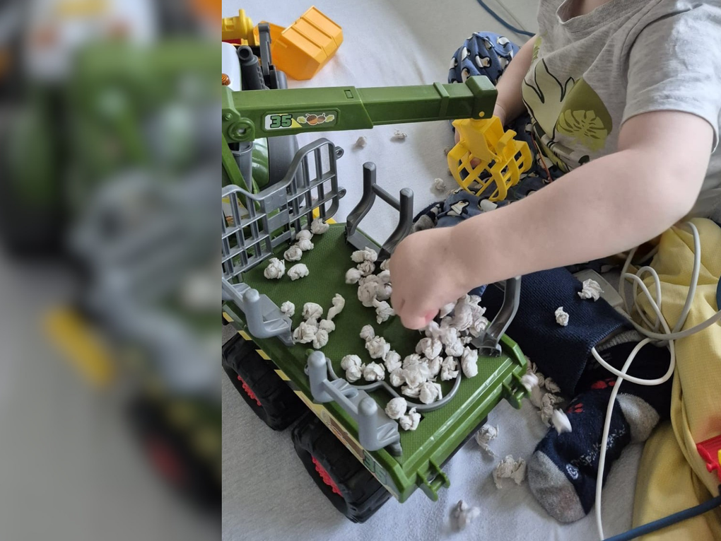 Ein Kind, das mit einem Spielzeugtraktor spielt Ein Kind, das mit einem Spielzeugtraktor spielt