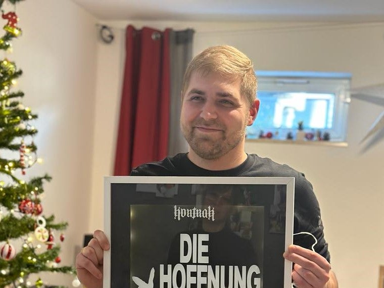 Ein Mann hält ein Schild vor einem Weihnachtsbaum Ein Mann hält ein Schild vor einem Weihnachtsbaum