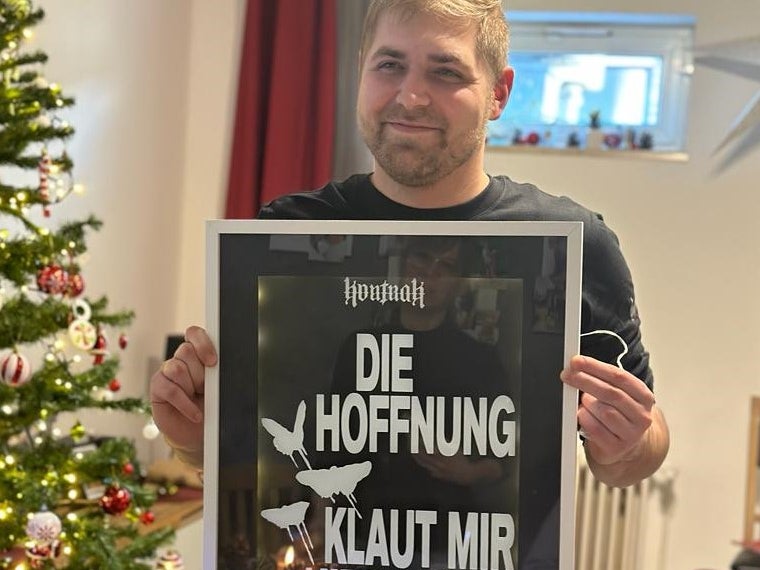 Ein Mann hält ein Schild vor einem Weihnachtsbaum Ein Mann hält ein Schild vor einem Weihnachtsbaum