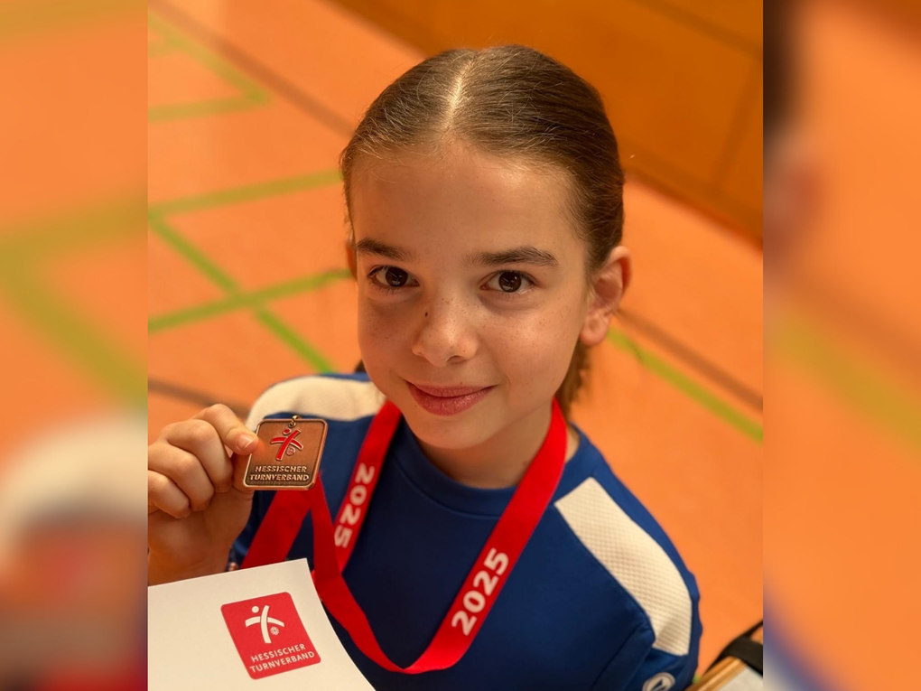 Ein Mädchen hält eine Medaille in die Kamera. Ein Mädchen hält eine Medaille in die Kamera.