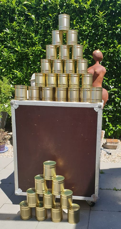 Eine Gruppe von Dosen, die auf und vor einer Kiste gestapelt sind Eine Gruppe von Dosen, die auf und vor einer Kiste gestapelt sind