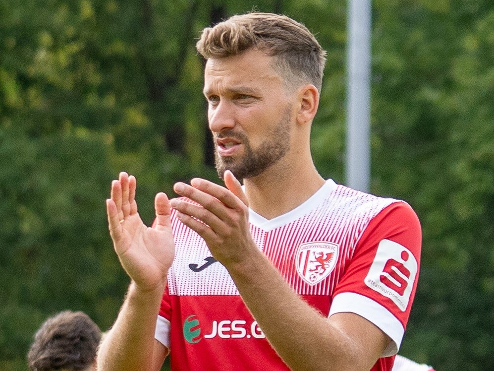 Ein Mann in einem rot-weißen Trikot klatscht Ein Mann in einem rot-weißen Trikot klatscht