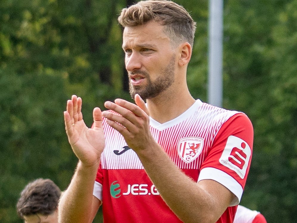 Ein Mann in einem rot-weißen Trikot klatscht Ein Mann in einem rot-weißen Trikot klatscht