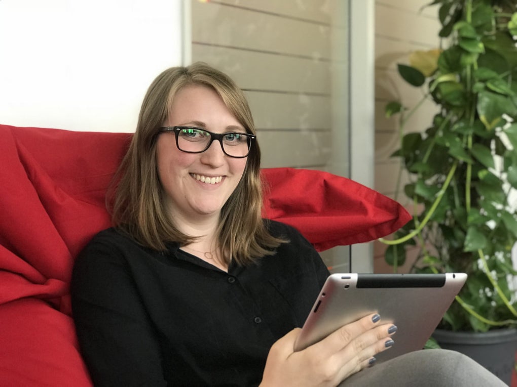 Sara von Knobelsdorff sitzt auf einem roten Kissen und hält ein Tablet Sara von Knobelsdorff sitzt auf einem roten Kissen und hält ein Tablet