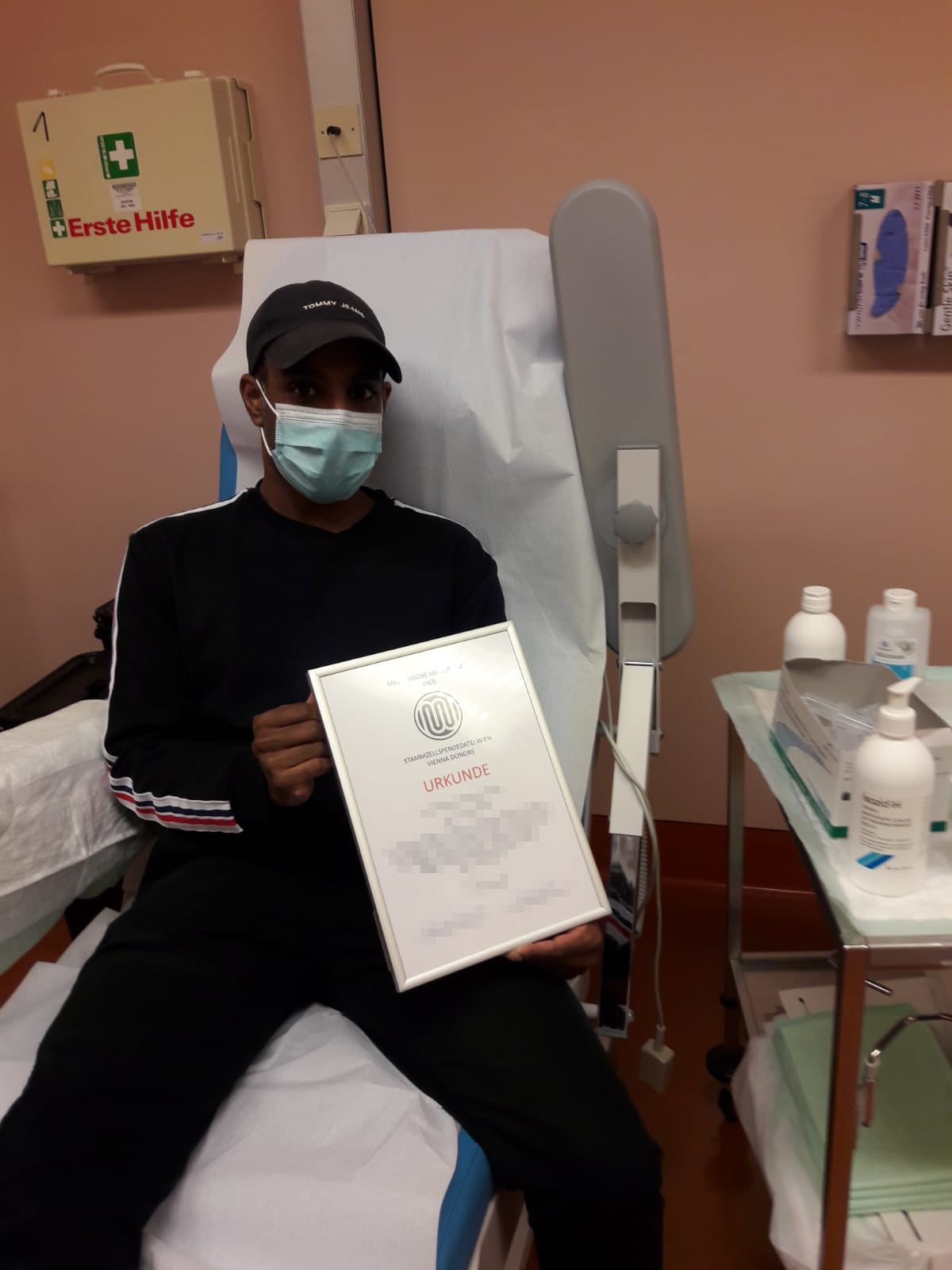 Dominique erhielt nach seiner Spende eine Urkunde, er liegt mit Maske in einem Bett Dominique erhielt nach seiner Spende eine Urkunde, er liegt mit Maske in einem Bett
