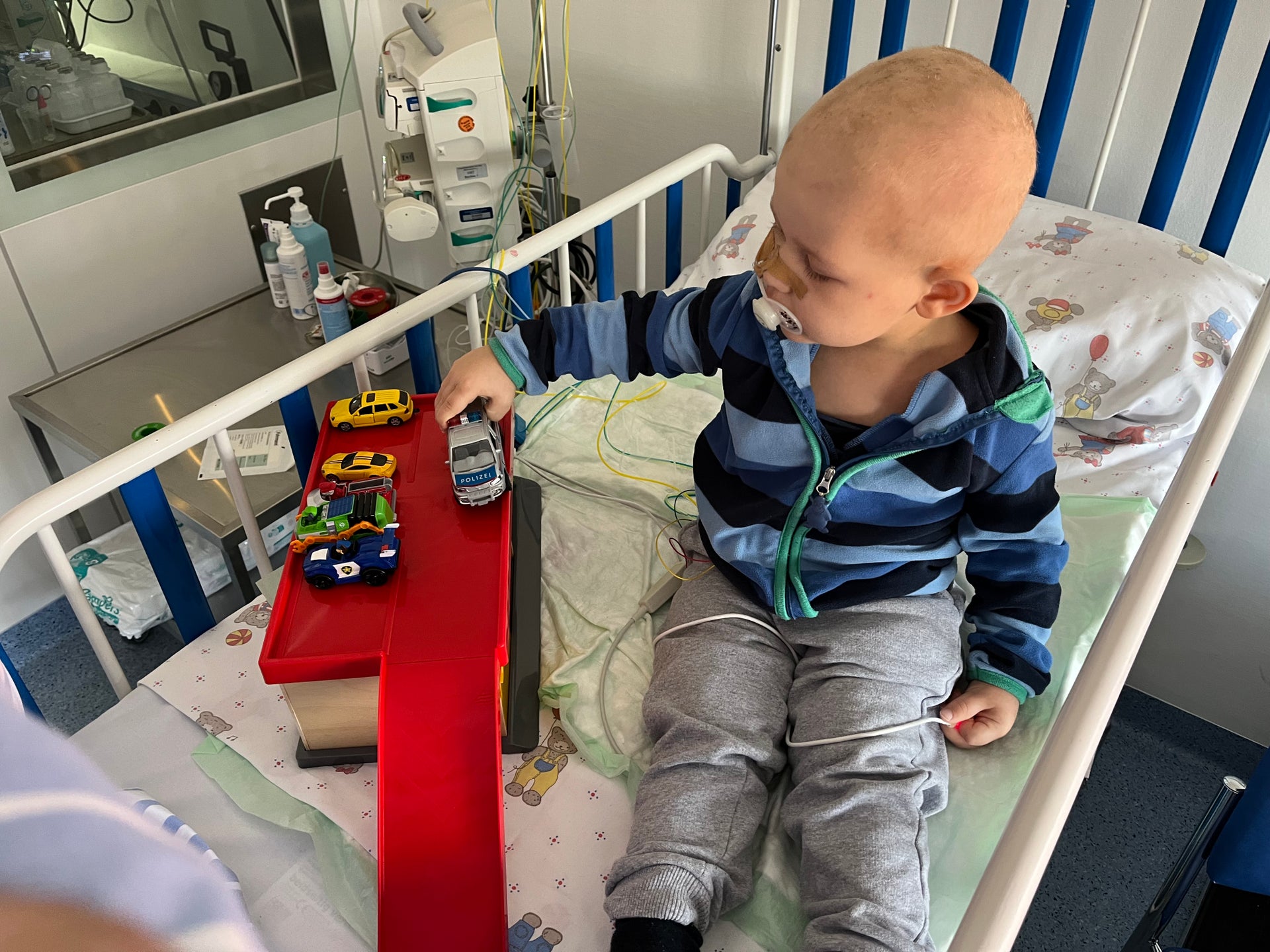 kleiner Junge sitzt auf einem Krankenhausbett und spielt mit Autos kleiner Junge sitzt auf einem Krankenhausbett und spielt mit Autos