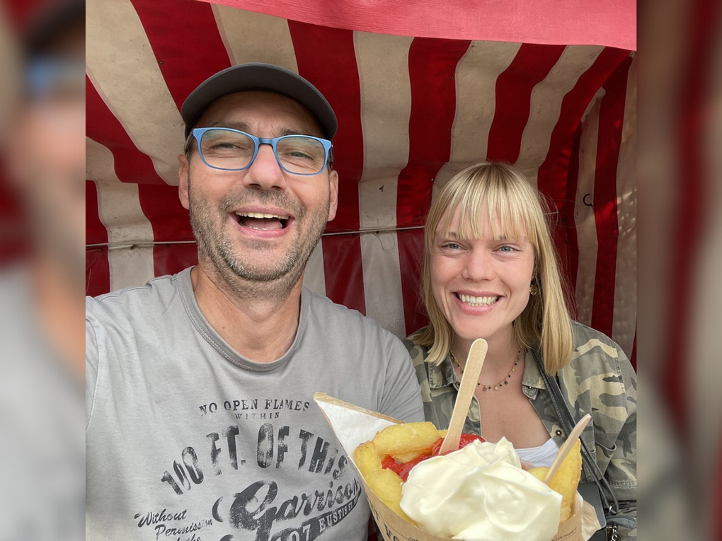 Ein Mann und eine Frau sitzen lachend in einem rot-weiß gestreiften Strandkorb mit einer Tüte Pommes Frites. Ein Mann und eine Frau sitzen lachend in einem rot-weiß gestreiften Strandkorb mit einer Tüte Pommes Frites.
