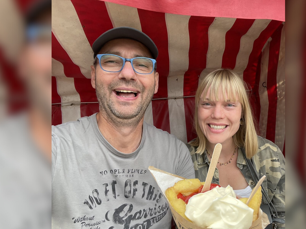 Ein Mann und eine Frau sitzen lachend in einem rot-weiß gestreiften Strandkorb mit einer Tüte Pommes Frites. Ein Mann und eine Frau sitzen lachend in einem rot-weiß gestreiften Strandkorb mit einer Tüte Pommes Frites.
