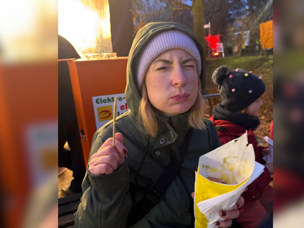 Eine Frau isst aus einer Tüte Pommes und kneift dabei die Augen zu. Eine Frau isst aus einer Tüte Pommes und kneift dabei die Augen zu.